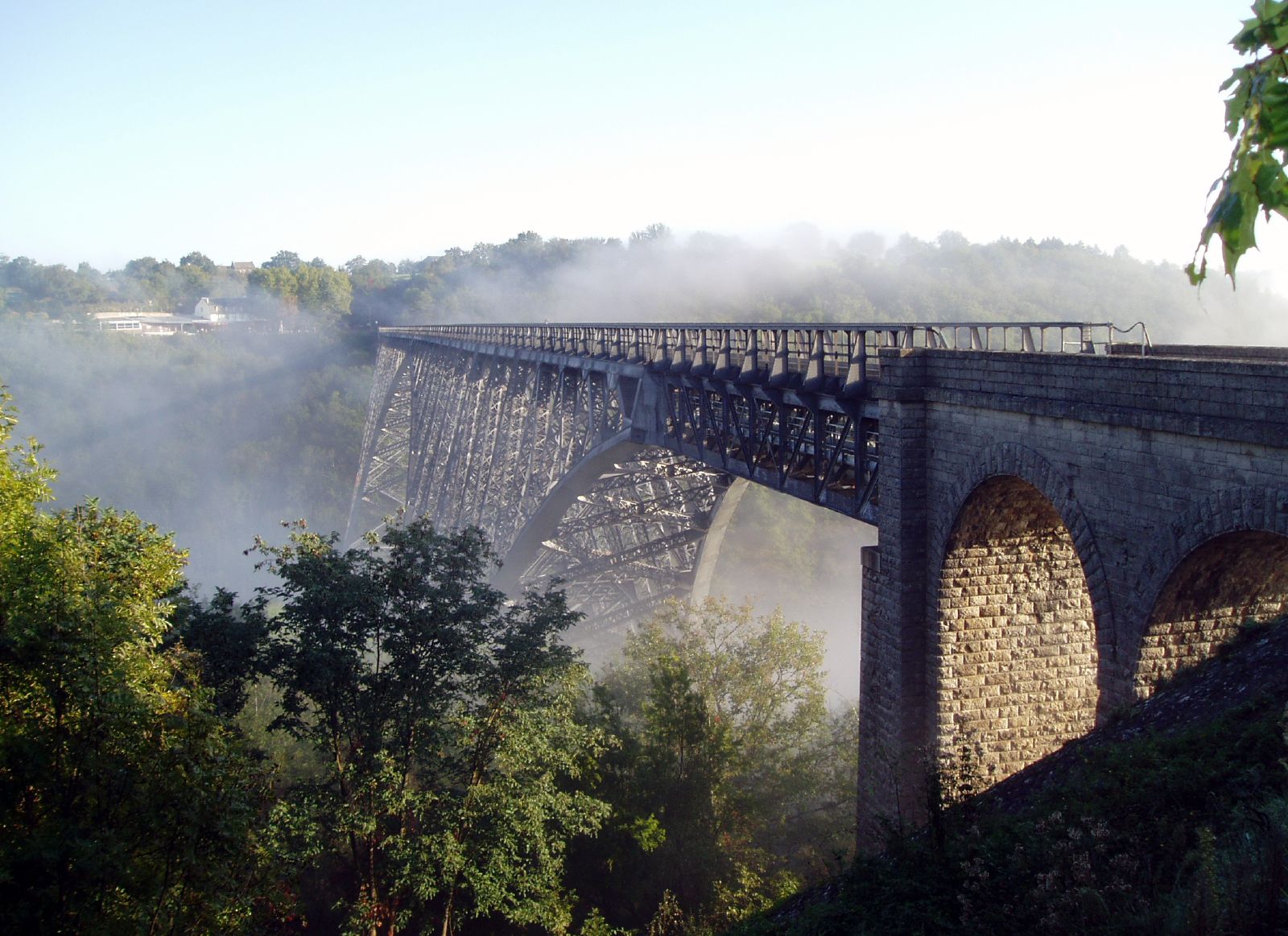 A steel rail viaduct crossing a misty river valley